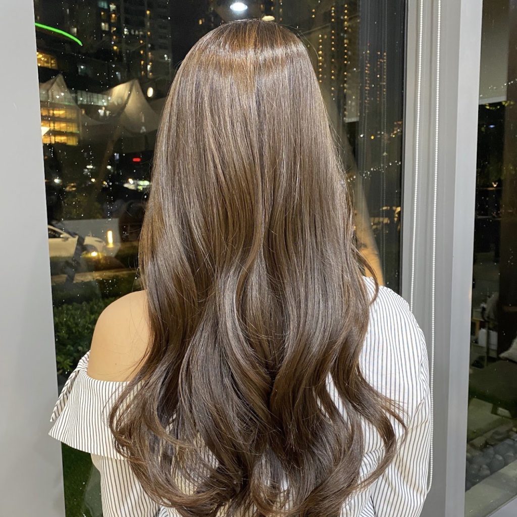 Long wavy hair in a soft ash beige without bleach, seen from behind