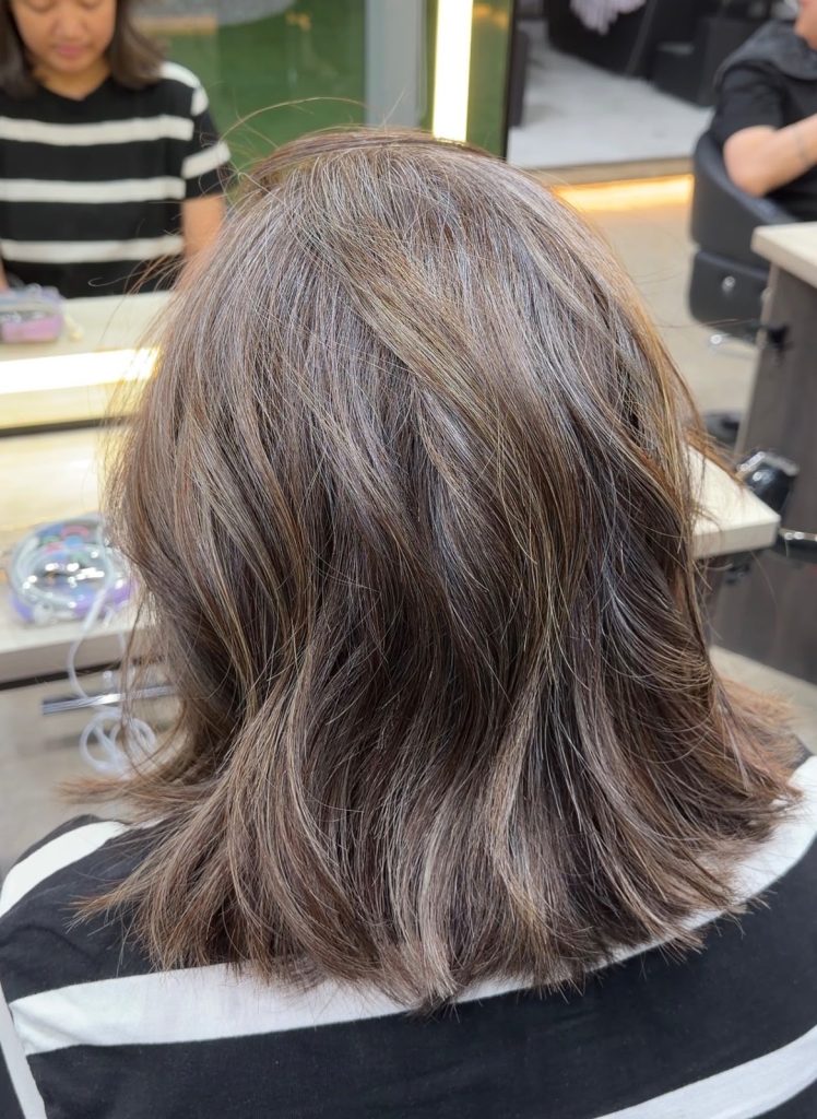 Medium-length hair with grey blended into soft brown highlights, seen from behind