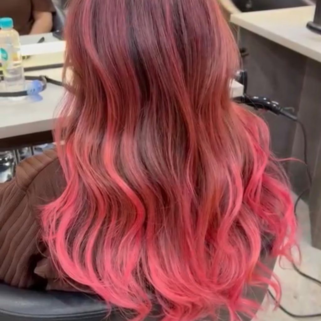 Long wavy hair with a vivid pink balayage, seen from behind