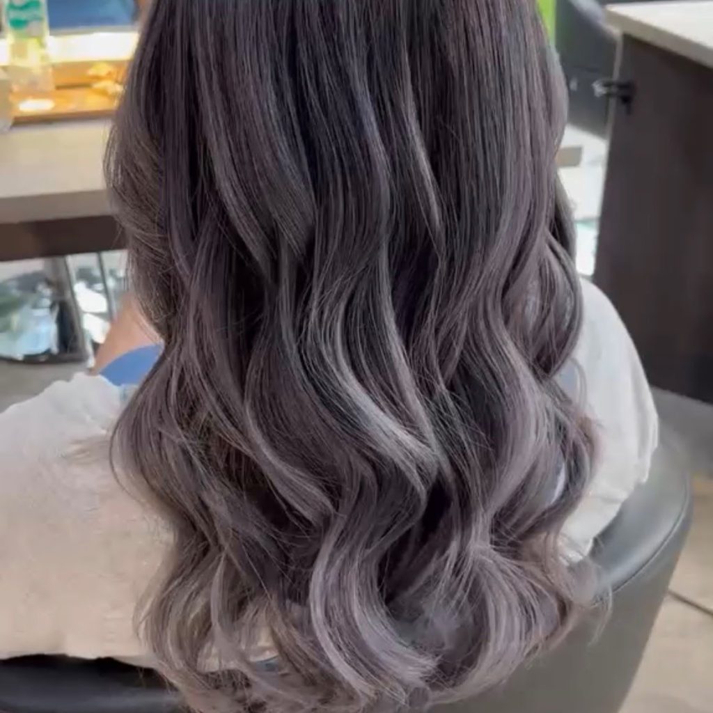 Long layered hair with a smoky silver grey balayage, seen from behind